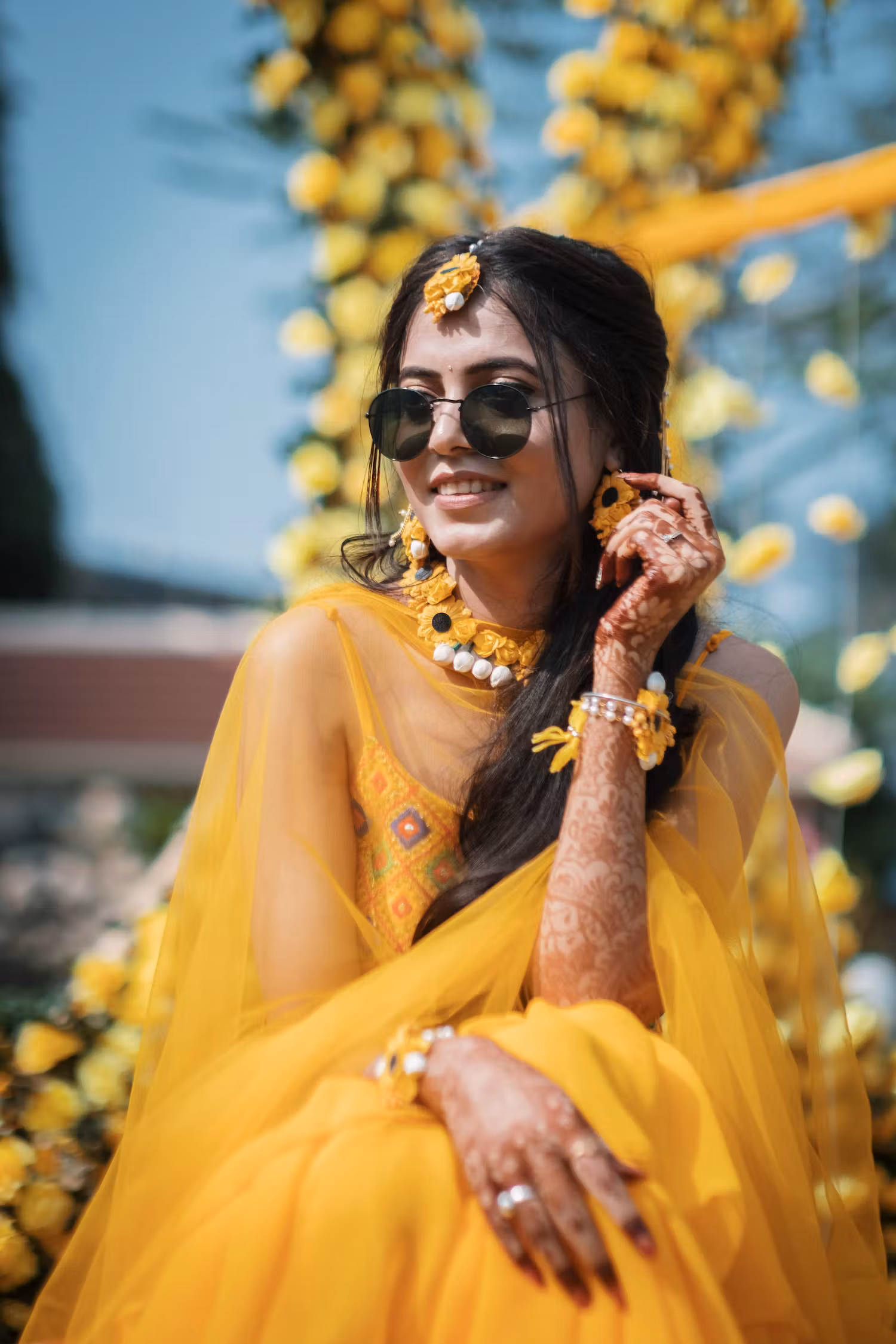 Bride posing to the cameras in a yellow lehenga and black sunglasses