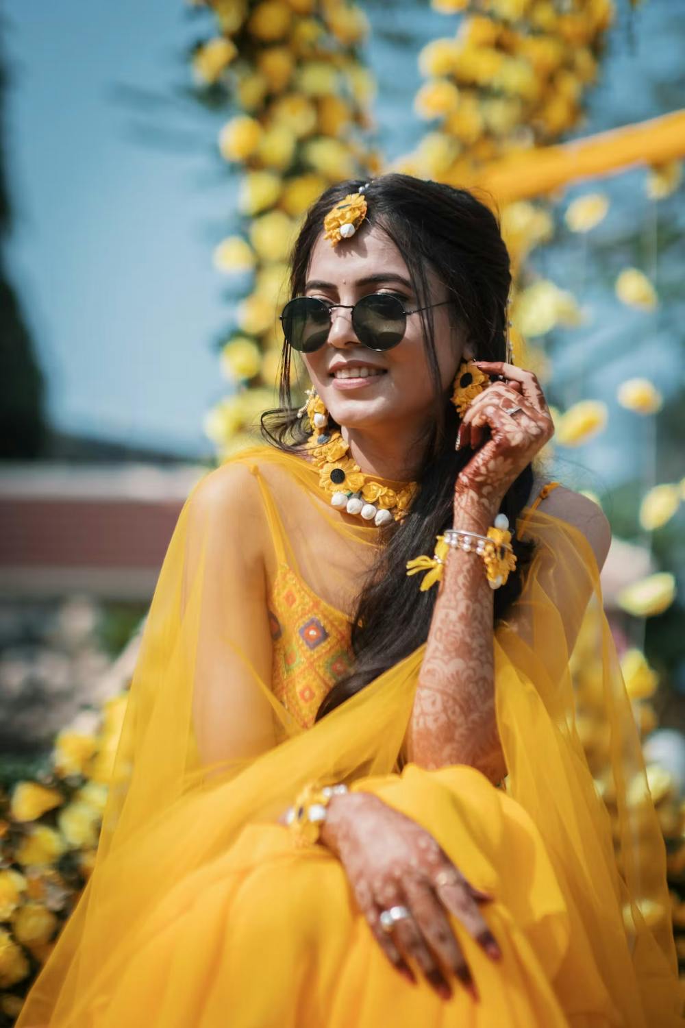 Bride posing to the cameras in a yellow lehenga and black sunglasses