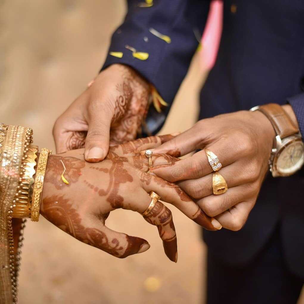 Groom putting ring on bride's finger on engagement day pic