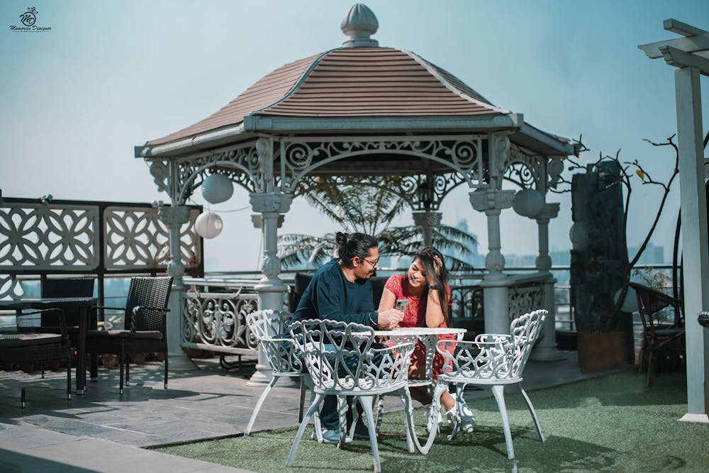 Couple chatting in a rooftop cafe for their candid pre-wedding photoshoot pic