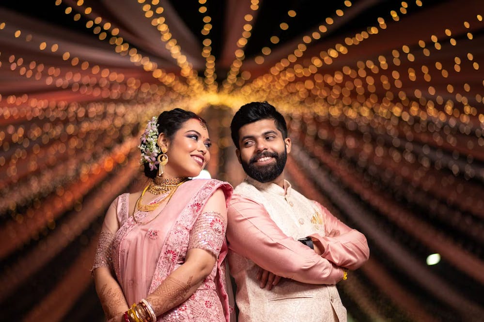 Groom posing in peach kurta with Nehru coat with his bride