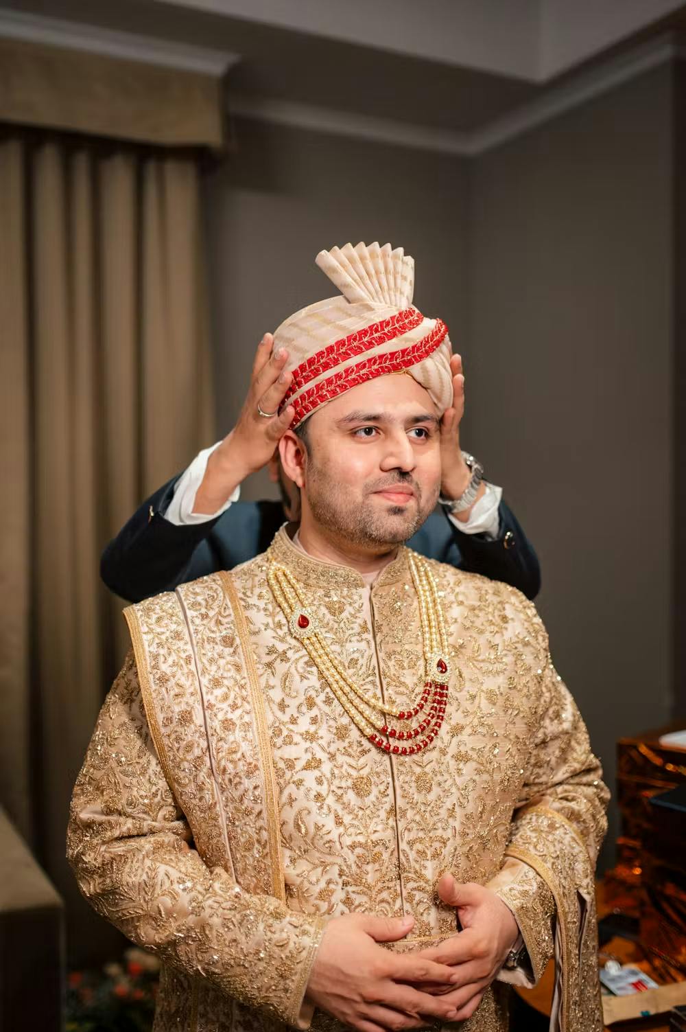 A friend placing turban on groom's head pic