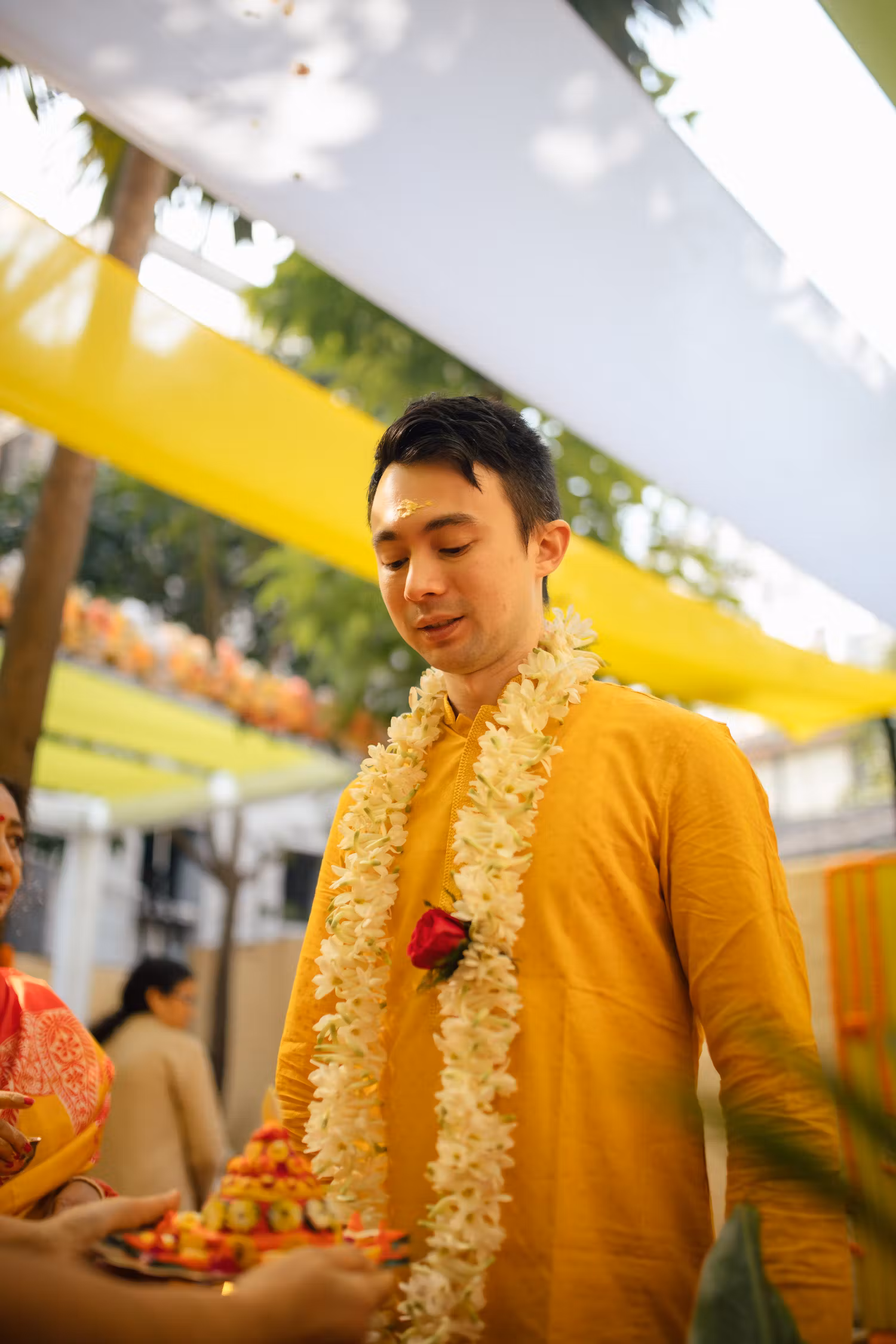Groom performing Haldi rituals with a white floral garland around his neck