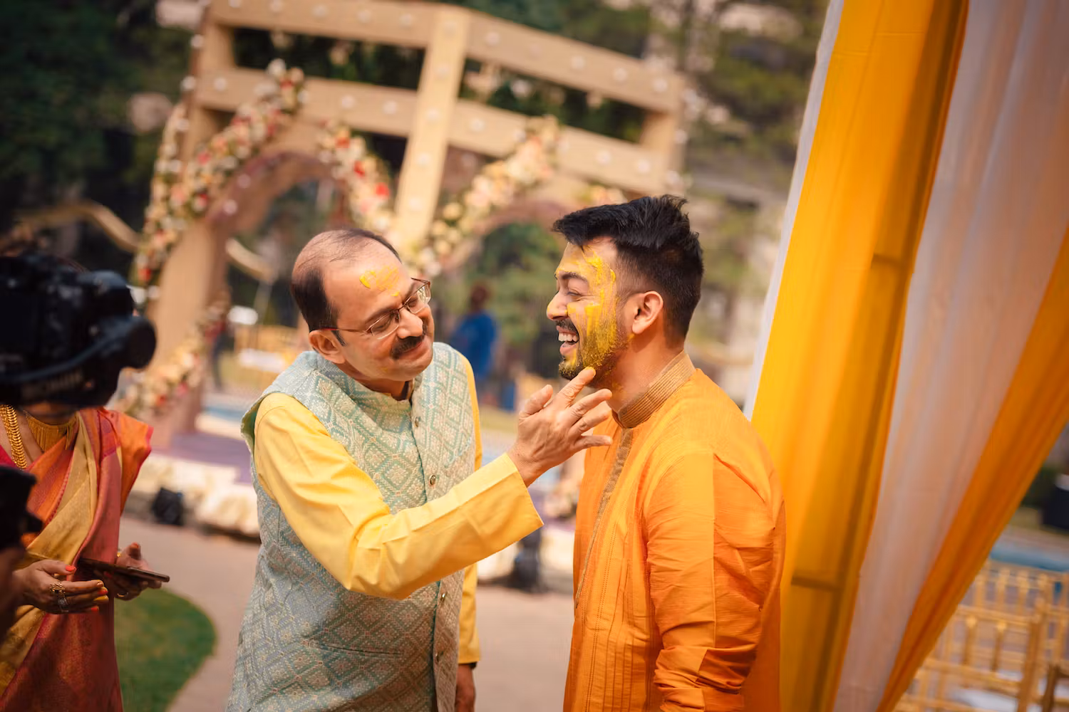 Father of groom applying turmeric paste on groom