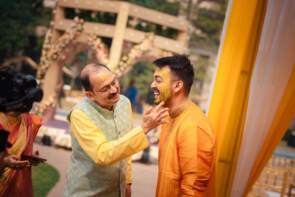 Father of groom applying turmeric paste on groom