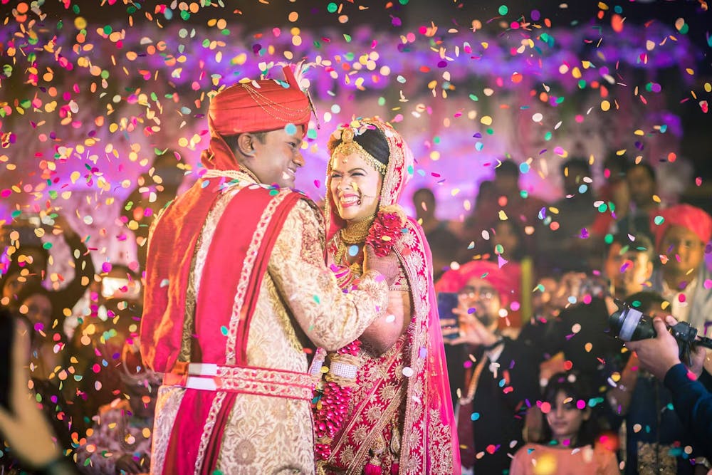 Indian bride and groom laughing during confetti shower | Cinematic wedding photoshoot | Memories Designer