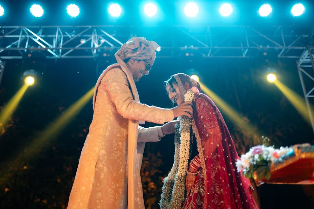 Creative wedding photography ideas for Indian bride and groom during garland exchange on stage| Memories Designer