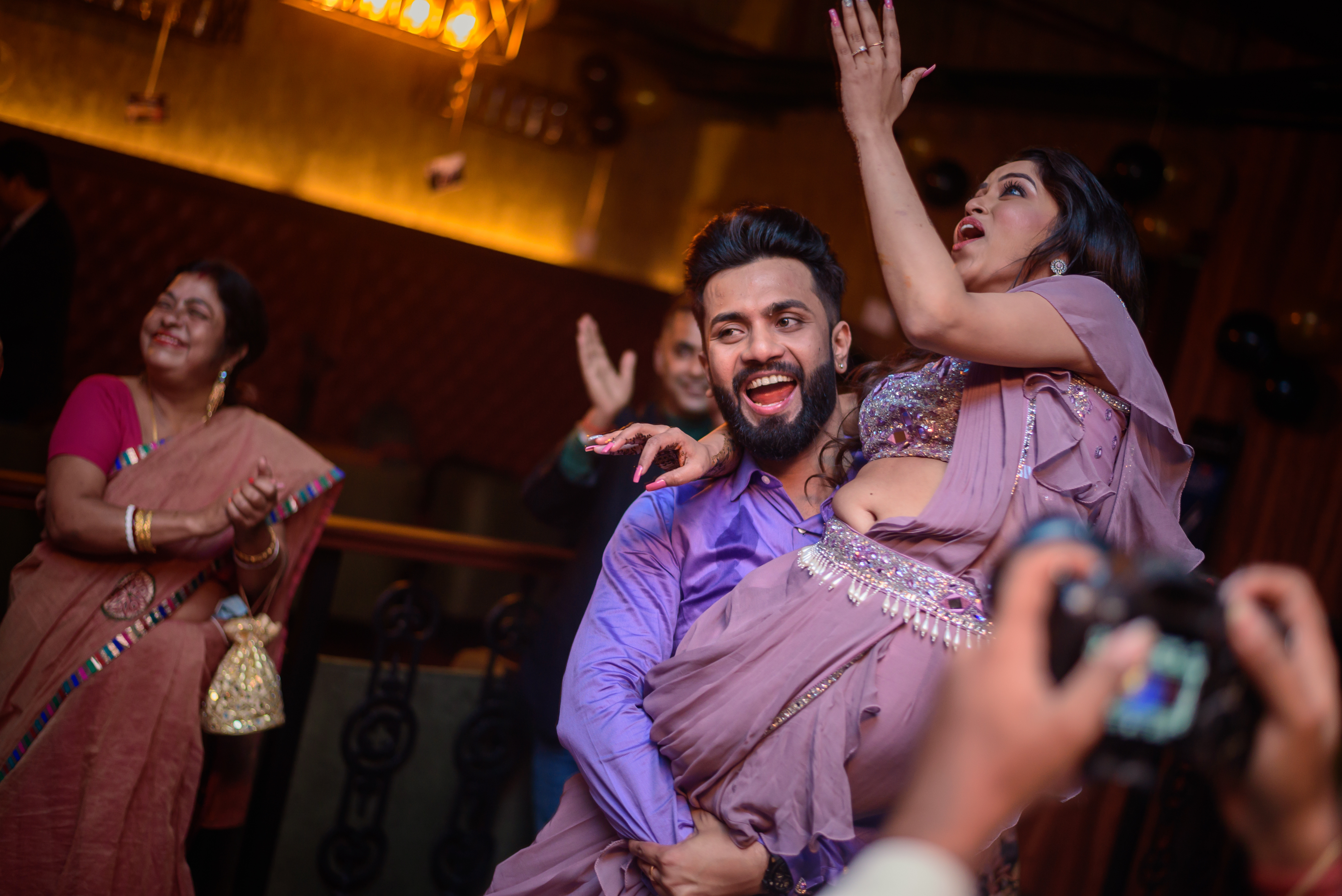 Groom wearing a shirt and lifting his bride pic