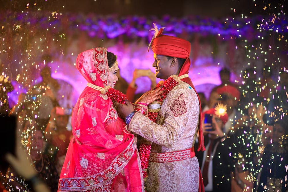 Groom in heavy sherwani while putting garland around bride's neck
