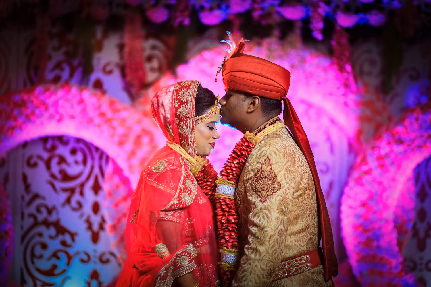 Wedding photoshoot where groom plants a forehead kiss on bride's forehead pic