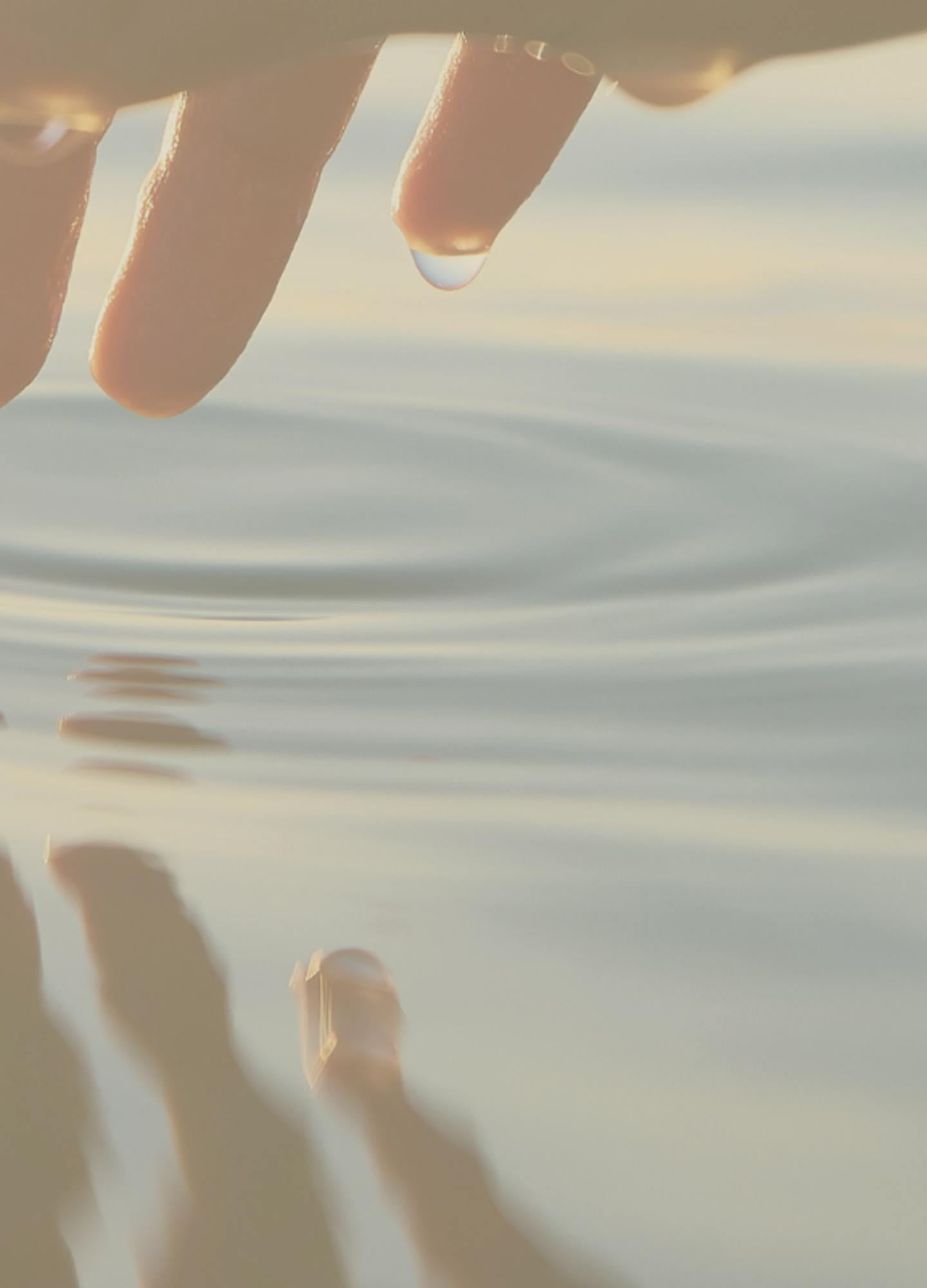 Fingertips gently touching the water creating a ripple effect