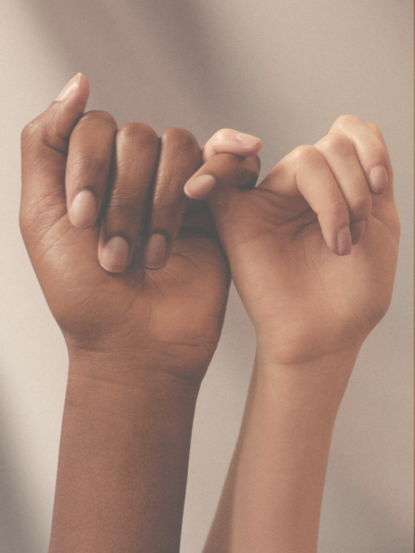 Two individual hands facing forwards, holding each others little fingers