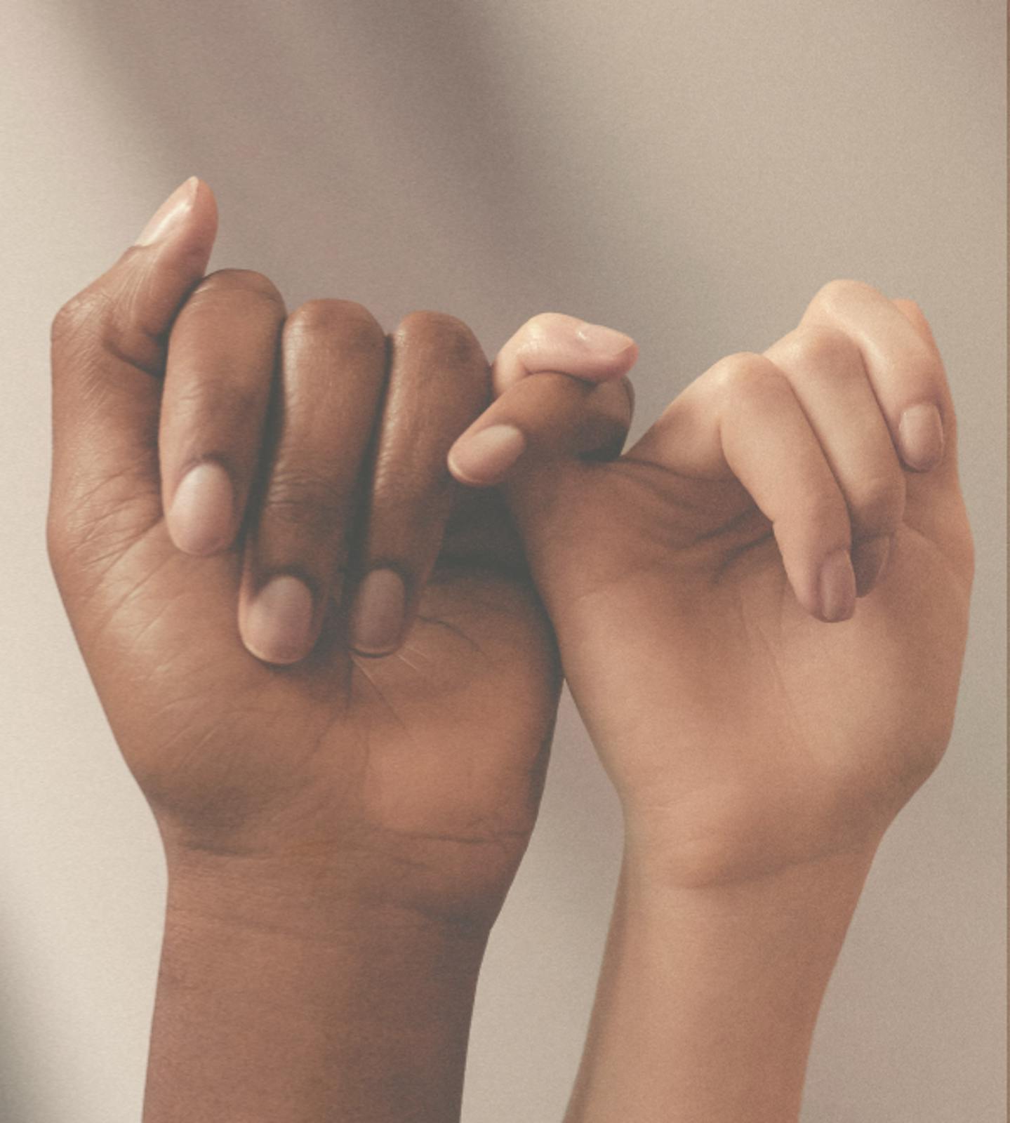 Two individual hands facing forwards, holding each others little fingers