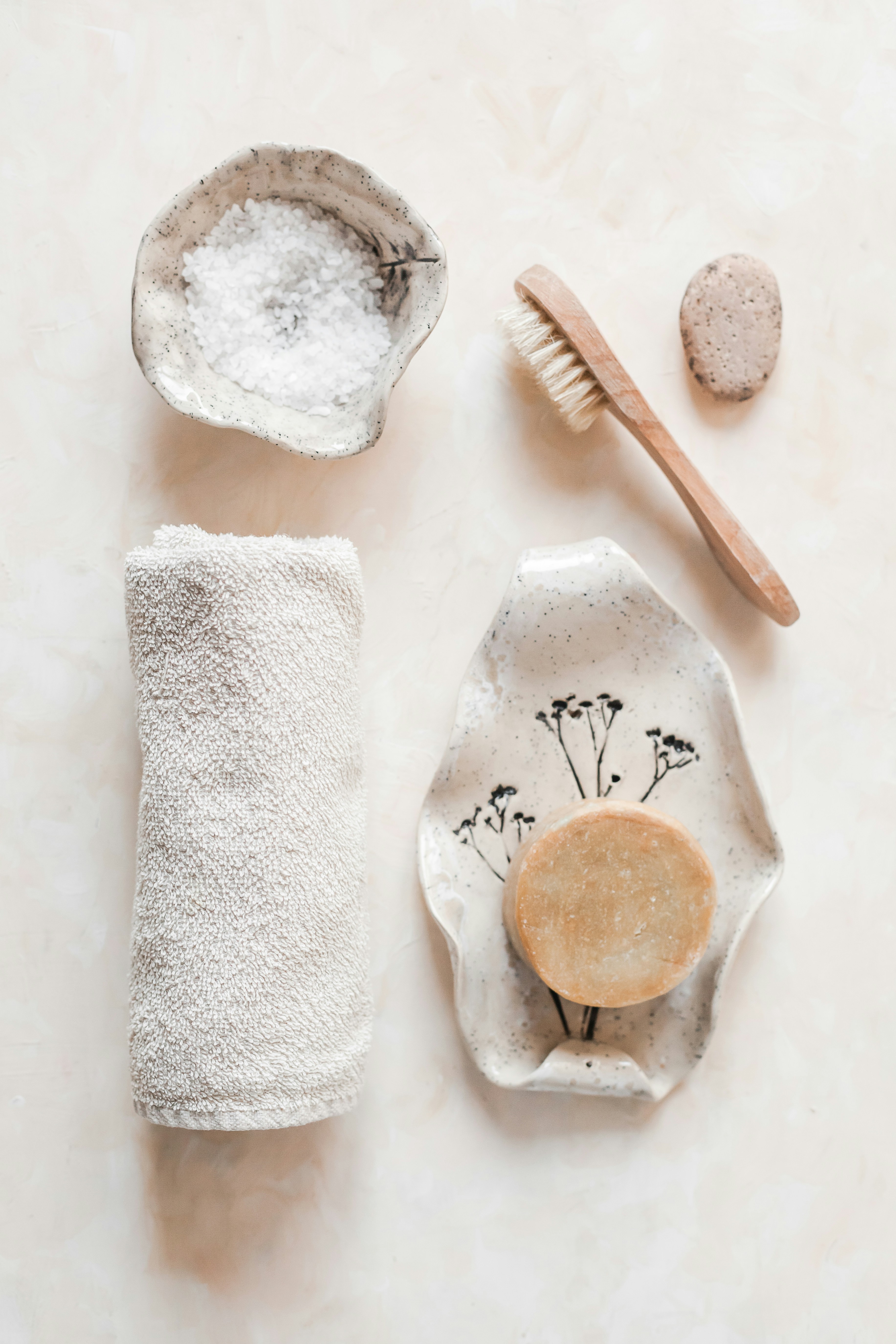 A collection of body tools: towel, salt, body brush, and soap