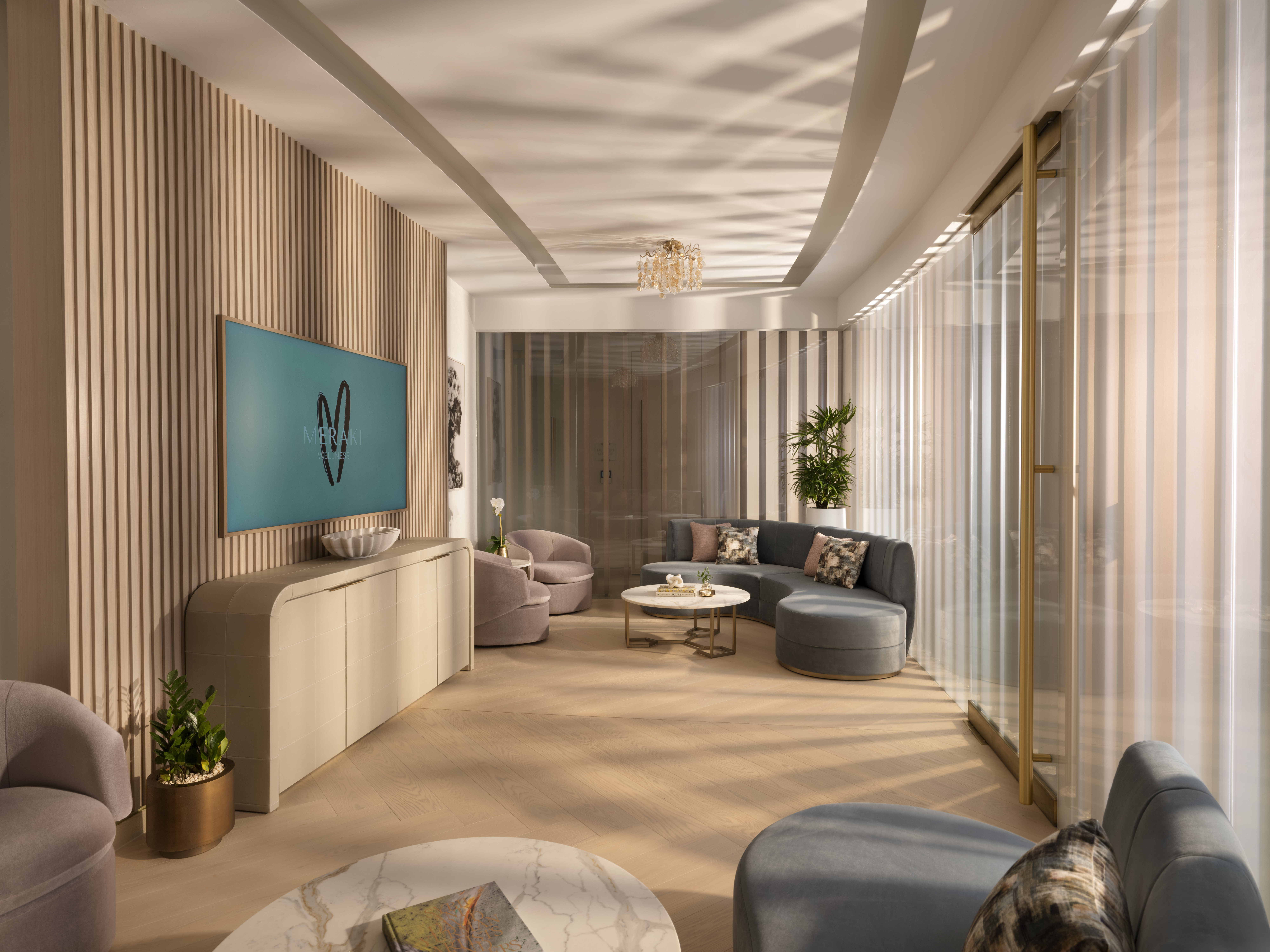 Meraki Wellness Grand Cayman Event Lounge with curved sofas and a TV screen 
