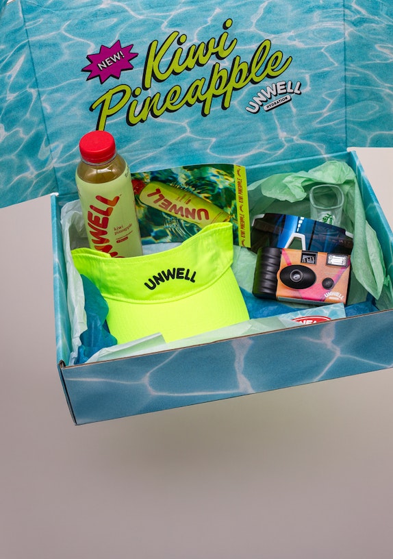 Unwell Hydration Kiwi Pineapple PR box with drink, neon visor, disposable camera, and sunglasses — MerchCamp custom merchandise