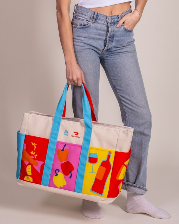 Full custom canvas jumbo grocery tote with colorful food illustration panels and blue-red straps, produced by MerchCamp for Doordash