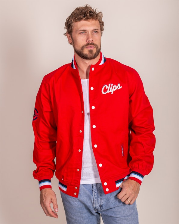 Full custom red snap-front varsity jacket with white script embroidery and striped ribbed cuffs, produced by MerchCamp for LA Clippers
