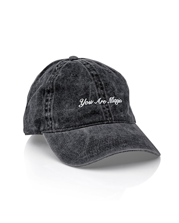 Embroidered vintage-wash black cotton dad hat with white cursive "You Are Magic" script, produced by MerchCamp for Logan Hollowell