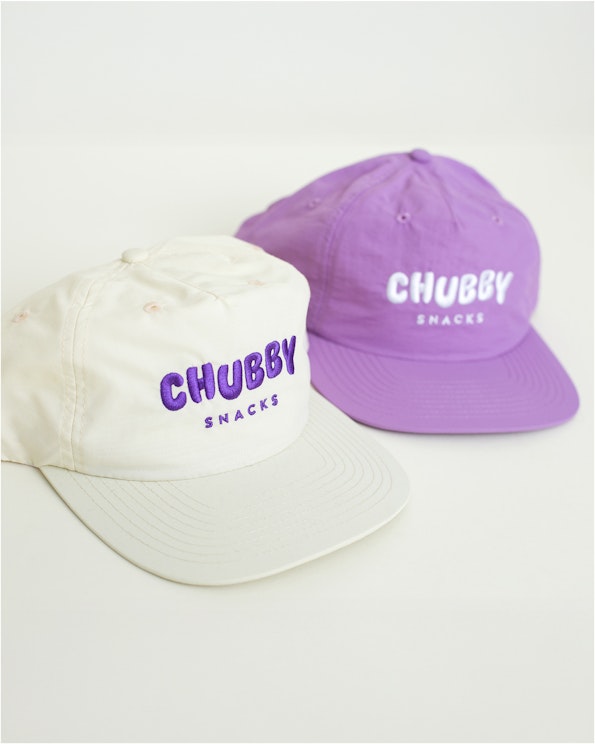 Embroidered cream and purple unstructured surf hats with puff letter branding, produced by MerchCamp for Chubby Snacks