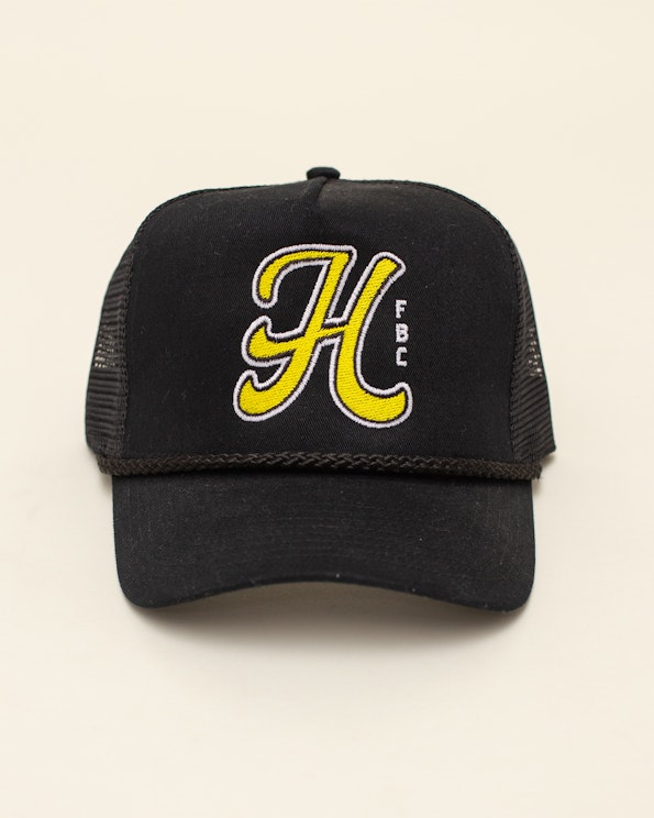 Embroidered black mesh trucker hat with yellow script H logo and rope detail, produced by MerchCamp