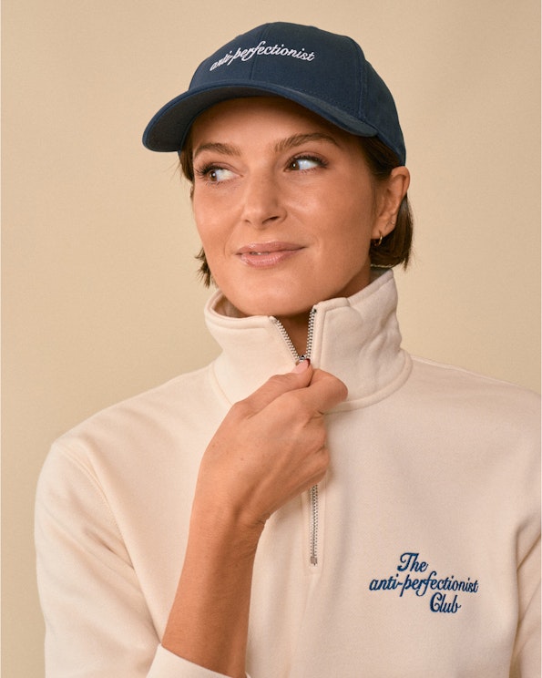 Embroidered navy cotton dad hat with white cursive "anti-perfectionist" script, produced by MerchCamp for How To Fail Podcast