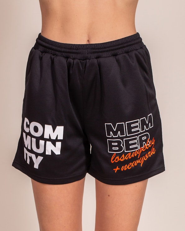 Full custom black mesh shorts with bold white and orange community member graphics, produced by MerchCamp for Community Member