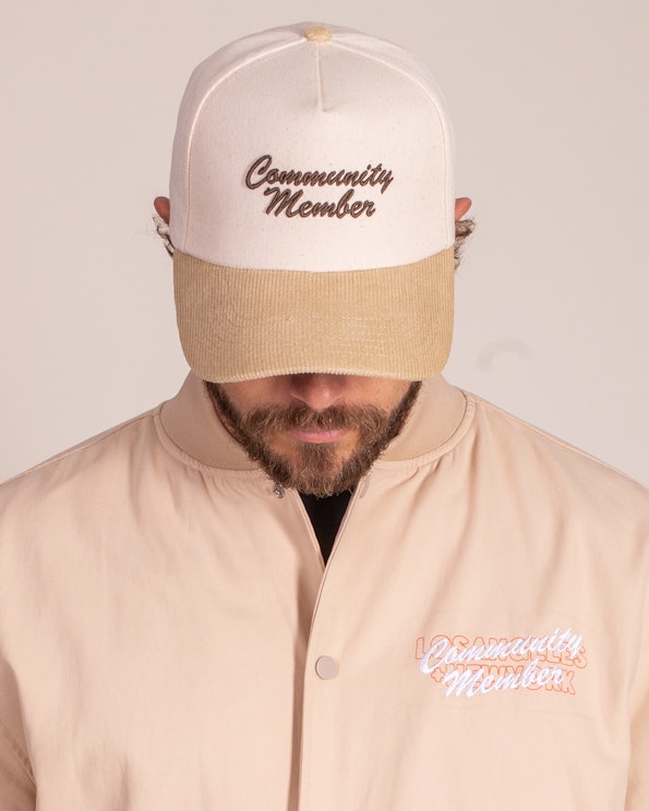 Embroidered cream canvas and tan corduroy snapback with brown script lettering, produced by MerchCamp for Community Member