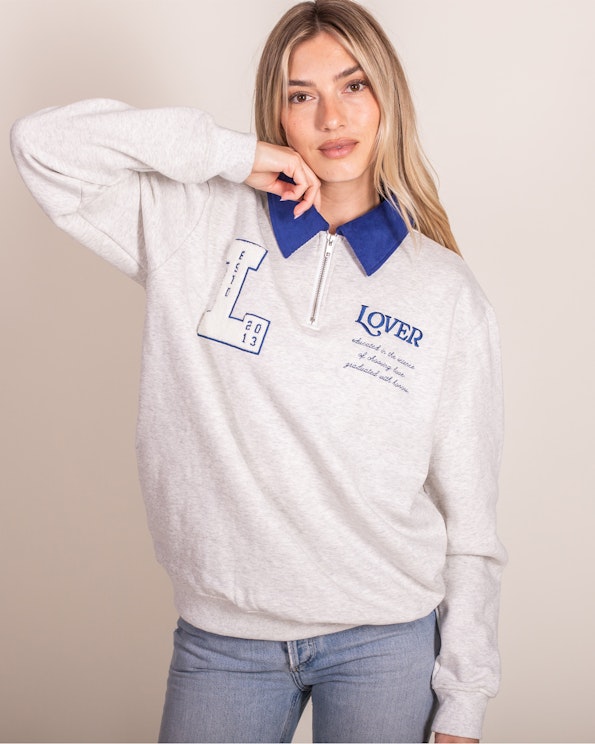Full custom heather grey quarter-zip sweatshirt with blue corded collar and embroidered text, produced by MerchCamp for Ruben Rojas
