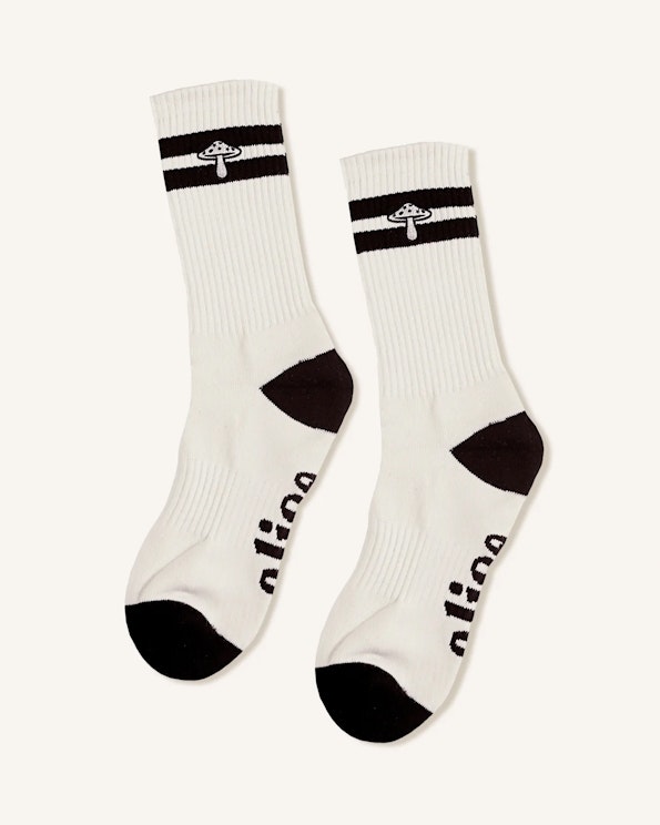 Full custom white ribbed crew socks with black mushroom motif and contrast heel and toe, produced by MerchCamp for Alice Mushrooms
