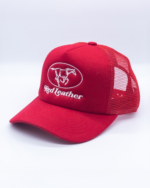 Embroidered red mesh-back trucker hat with white horse logo and script text, produced by MerchCamp for Red Leather