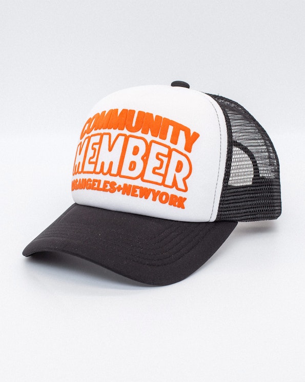 Puff printed black and white mesh trucker hat with orange community text graphic, produced by MerchCamp for Community Member