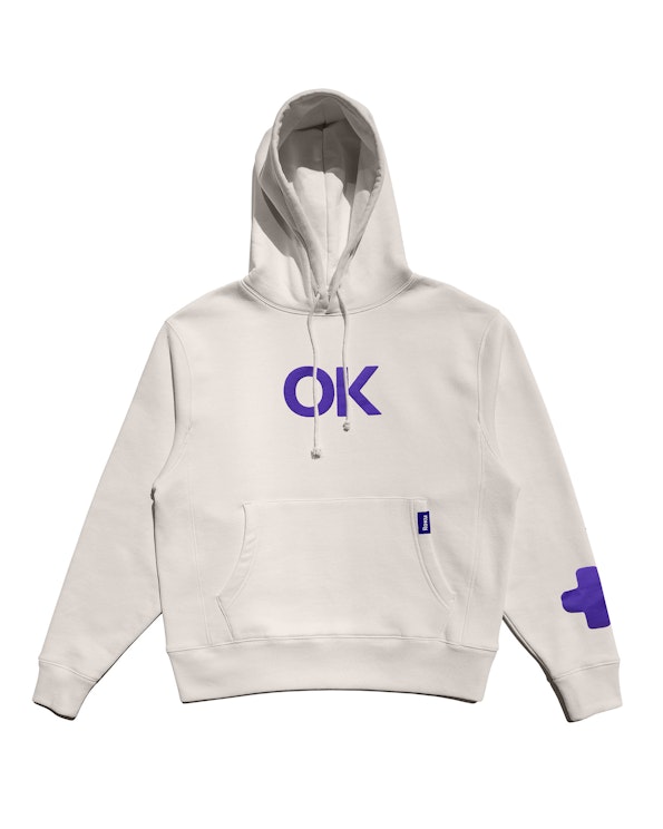 Screen printed cream fleece pullover hoodie with purple "OK" graphic and cross motif, produced by MerchCamp for Roku
