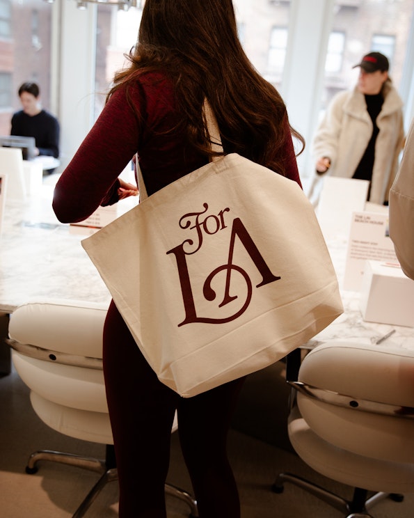 Screen printed natural canvas tote bag with dark burgundy serif typographic design, produced by MerchCamp for Community Member