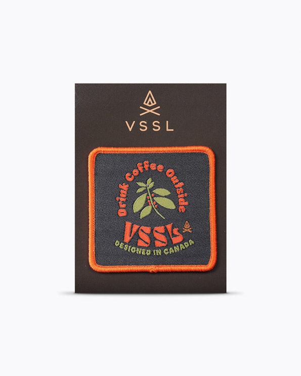 Custom woven patch with orange border, green coffee plant motif on navy fabric, produced by MerchCamp for VSSL Gear