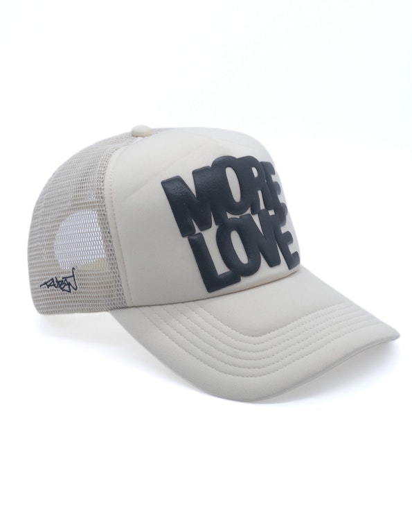 Puff printed cream mesh trucker hat with bold black "More Love" raised lettering, produced by MerchCamp for Ruben Rojas