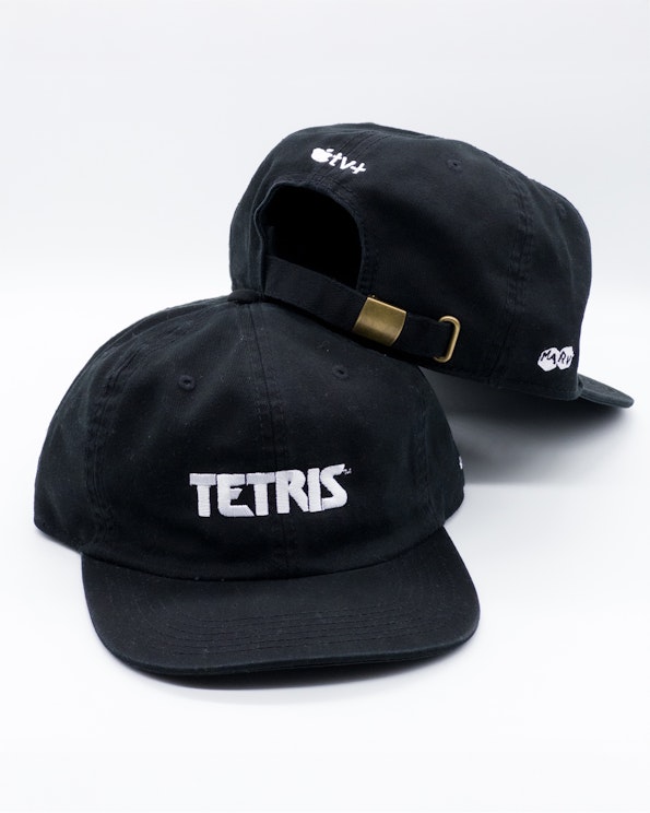Embroidered black cotton dad cap with white Tetris logo and brass buckle closure, produced by MerchCamp
