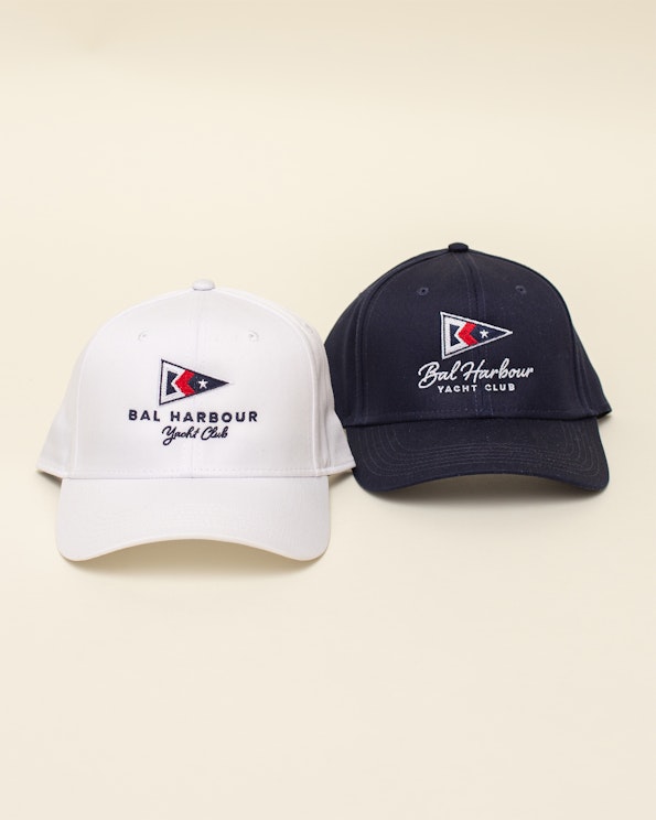 Embroidered white and navy cotton baseball caps with nautical pennant flag logo, produced by MerchCamp for Kitson Yachts