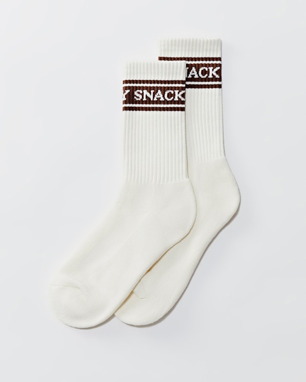 Full custom white ribbed crew socks with brown stripe band and "SNACKY" knit text, produced by MerchCamp for Snack TBH