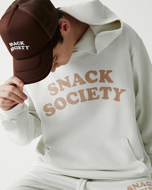 Screen printed cream fleece pullover hoodie with tan wavy brand lettering, produced by MerchCamp for Snack TBH