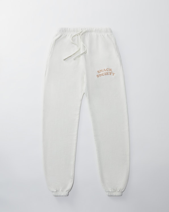Printed white fleece jogger sweatpants with tan "Snack Society" arch lettering, produced by MerchCamp for Snack TBH