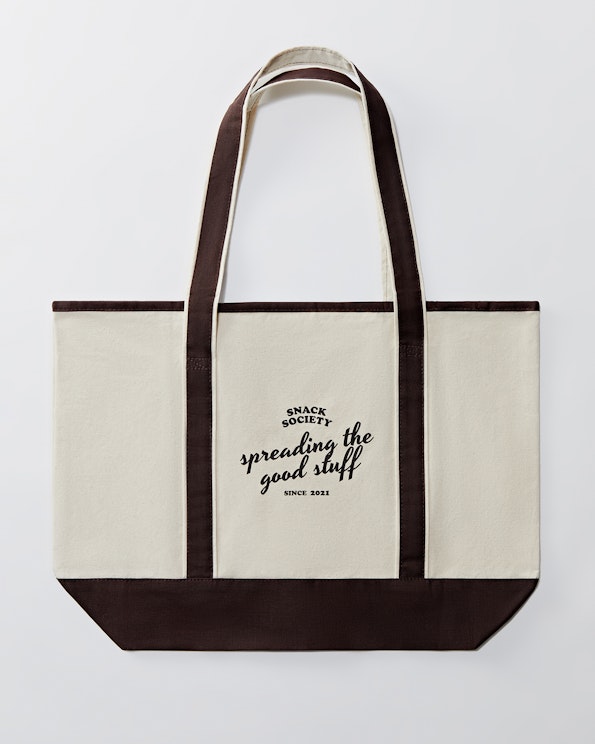 Printed cream and brown contrast canvas tote bag with script slogan design, produced by MerchCamp for Snack TBH