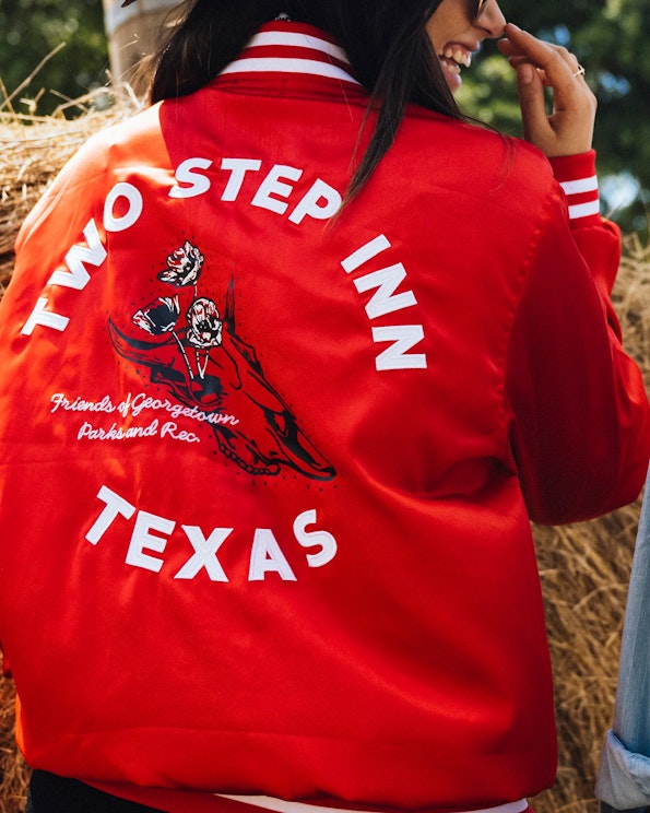 Embroidered red satin bomber jacket with longhorn skull graphic and white striped trim, produced by MerchCamp for Live Nation