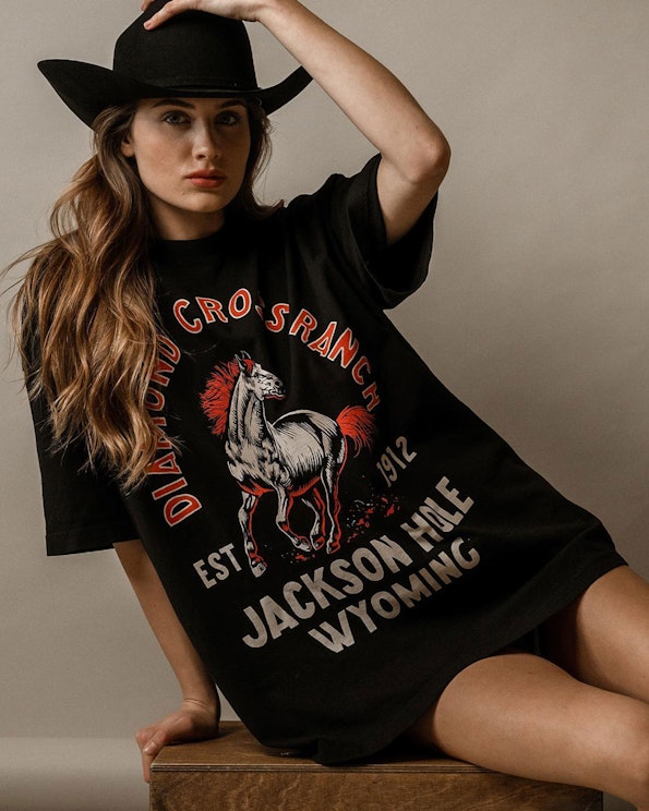 Screen printed black oversized graphic tee with vintage horse illustration and red text, produced by MerchCamp for Diamond Cross Ranch