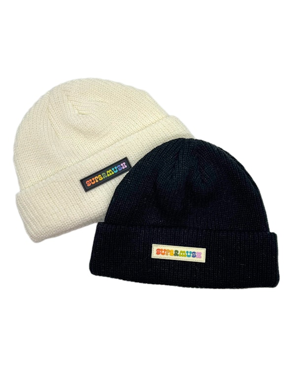 Full custom knit beanies in cream and black with rainbow PVC logo patches, produced by MerchCamp for Multiverse