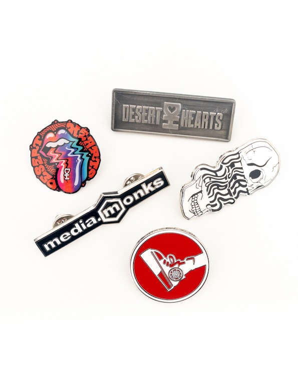 Custom enamel pin set with colorful lip logo, skull motif, and red circular design, produced by MerchCamp
