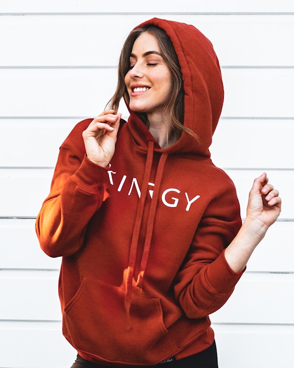 Screen printed rust red fleece pullover hoodie with white brand lettering, produced by MerchCamp for KINRGY