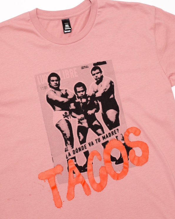 Screen printed pink cotton tee with halftone lucha libre graphic and orange TACOS text, produced by MerchCamp for Tu Madre