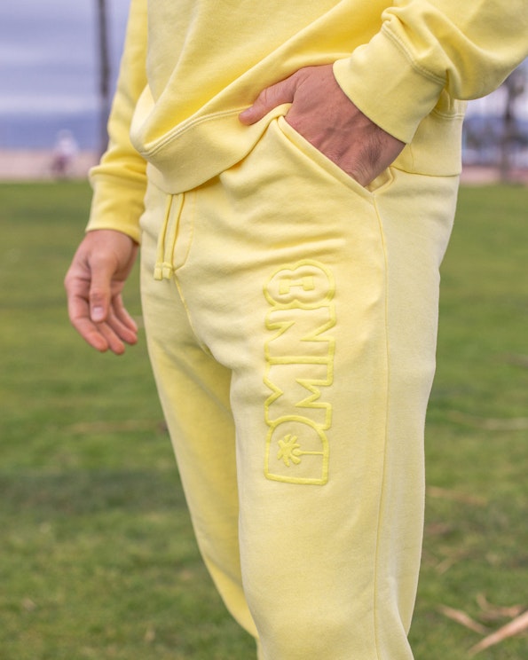 Puff printed yellow fleece joggers with tonal raised lettering and drawstring waist, produced by MerchCamp for DMN8