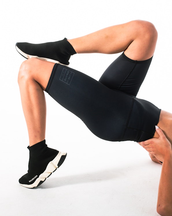 Custom black high-waist bike shorts with tonal logo print and compression fit, produced by MerchCamp for Live Athletic